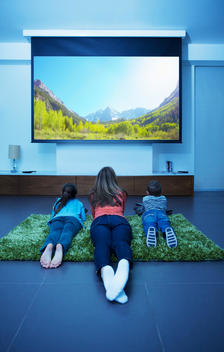 Mother and children watching television in living room