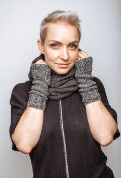 Portrait of beautiful woman with short blonde hair. Green eyes white background. Wearing winter scarf and mitts.
