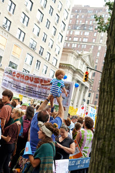 father holding high up his son at the climate march in new York