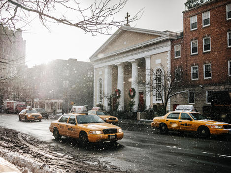 Taxis drive up the Avenue of the Americas in the snow during the holidays in New York City.