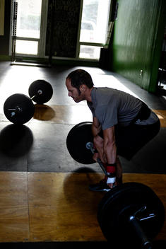 A Crossfit athete prepares to do a clean and jerk wtih barbell weights at a Crossfit gym.