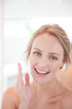 Smiling Woman with Moisturizing Cream on Hand