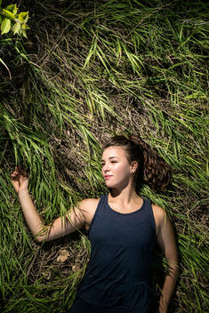 A girl in athletic wear laying in a field of grass.