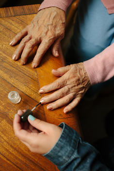 Woman painting senior woman\'s finger nails.