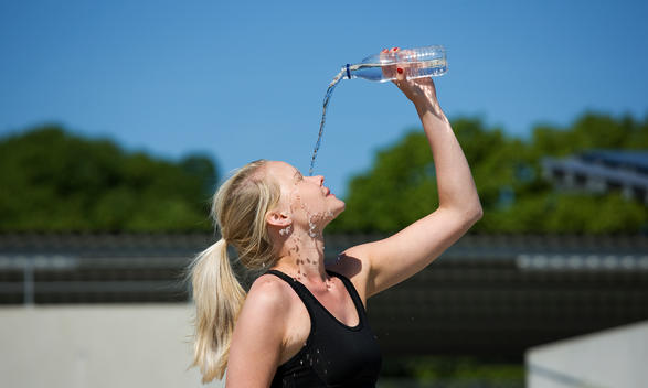 Woman in fitness outfit, pouring water on her face