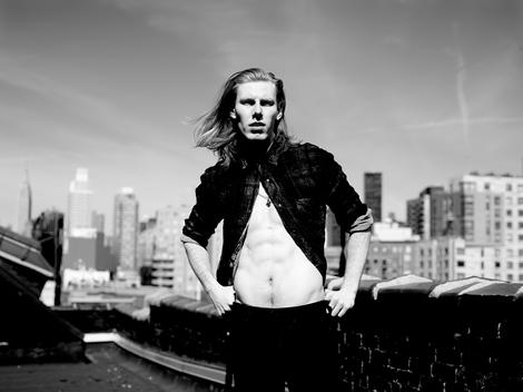 Male model with long blonde hair posing on NY rooftop