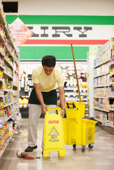 Mixed race man cleaning up spill in grocery store