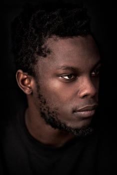 A portrait of a young man on black wearing black.