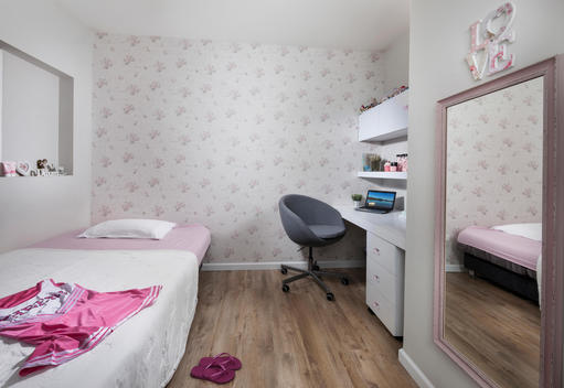 Modern House. Young girl\'s bedroom with floral wallpaper and rectangle mirror across from bed.