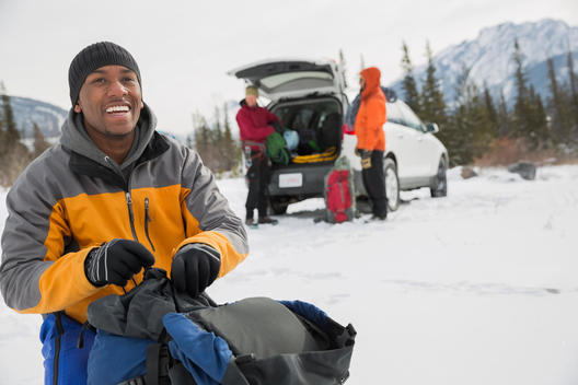 Smiling man with friends preparing for winter hike in mountains
