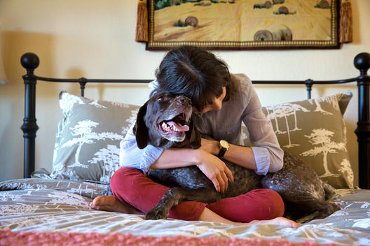 Woman hugging dog on bed
