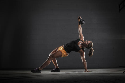 Girl lifting a kettle bell in a crossfit gym