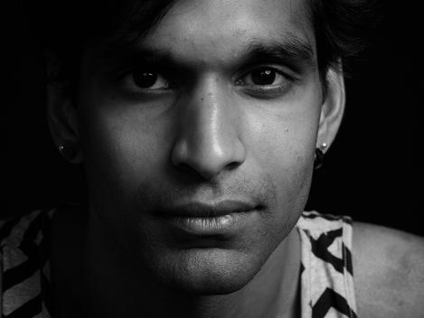 Black background portrait of young late 20?s Indian male.