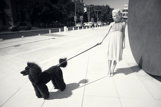 Urban black and white image of a blonde model and black dog