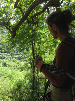 Woman preparing to zip-line across ravine in jungle