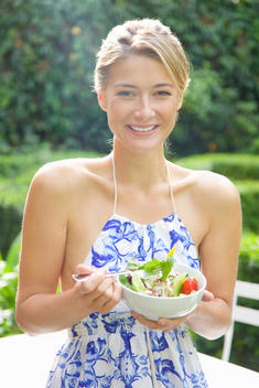 Woman Eating Salad in Garden Smiling