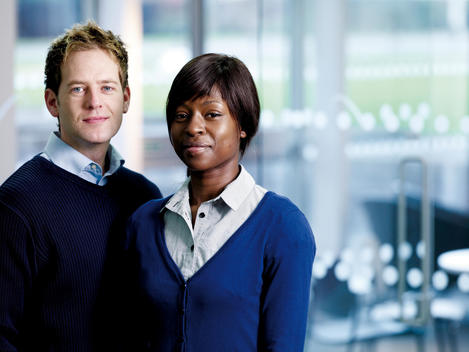 Young Woman, African Appearance, Portrait With Young Man, Caucasian Appearance, Both Wearing Blue Sweaters.