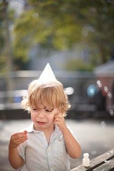 A photo of a little boy upset with his party hat