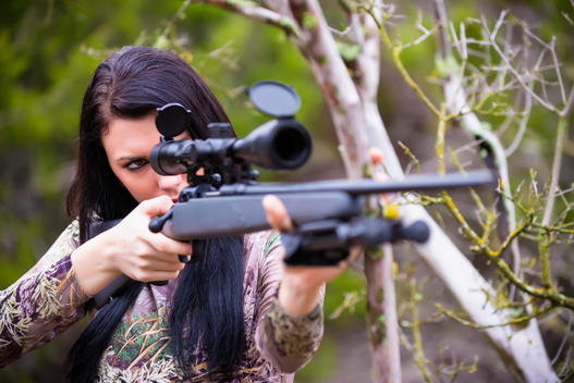 USA, Texas, Young woman aiming with hunting rifle