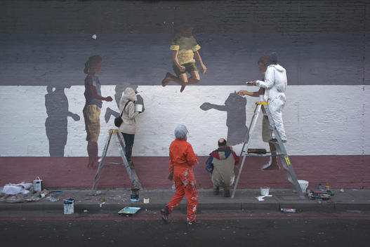 Four people create street art on a brick wall in East London