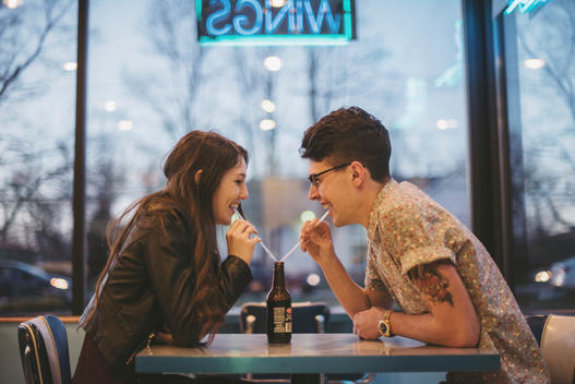 Couple laughing while sharing a drink at an old fashioned burger joint