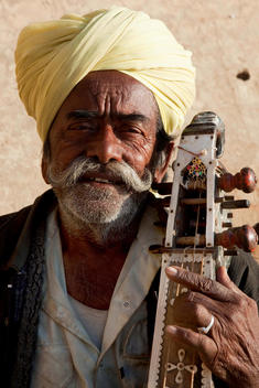 Indian man wearing turban and playing traditional instrument from Rajasthan