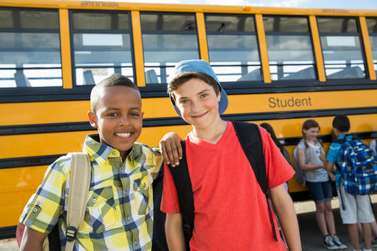 Portrait of schoolboys standing in front of bus during field trip