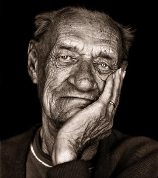 Portrait of grandfather holding his face with slight smile in black and white.