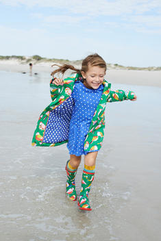 girl with rain boots running in to the sea near the shore