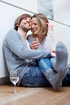 Couple sitting on kitchen floor with wine