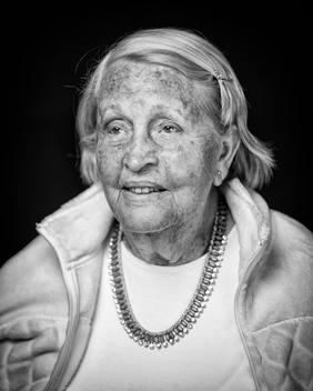 Black and white portrait of elderly woman necklace smiling away from camera