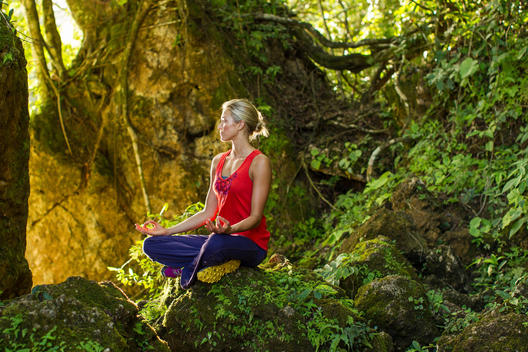 Woman meditating in yoga pose, rain forest