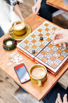 Cropped image of friends playing board game at cafe table