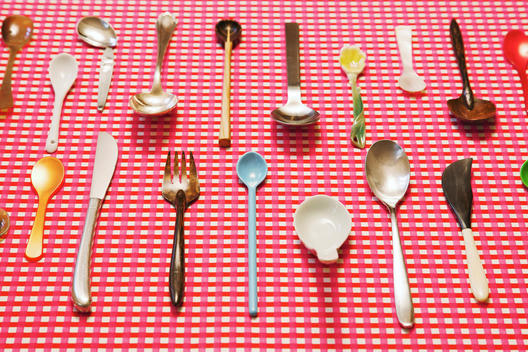 Still life of knife, forks and spoons on red white square pattern