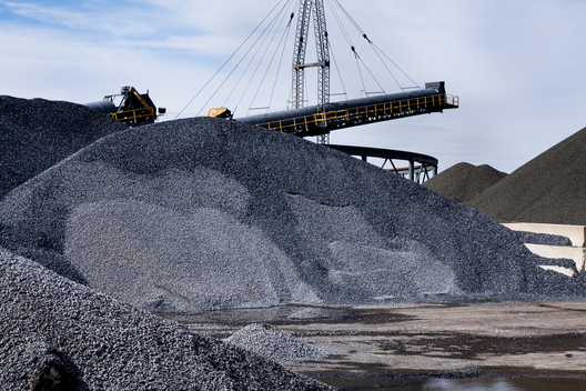 Gray gravel and sand piles in industrial construction yard with big blue sky