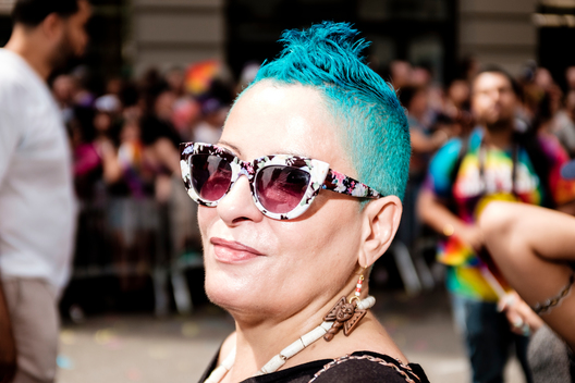 A woman with a turquoise faux hawk watches the 2015 NYC Pride March (Gay Pride Parade).