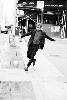 model in designer suit playing soccer in Manhattan