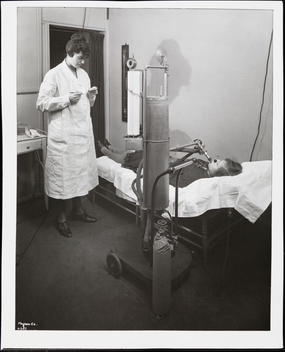 An Unidentified Woman With A Medical Machine Attached To Her Mouth, Perhaps Measuring Her Breathing, While A Nurse Watches.