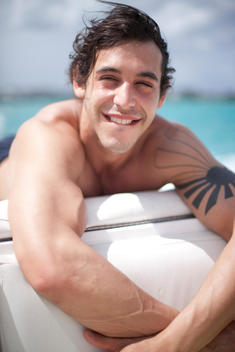 A photo of a muscular guy enjoying some sun on a boat