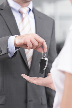 At the car dealer, Salesman handing over car key to client