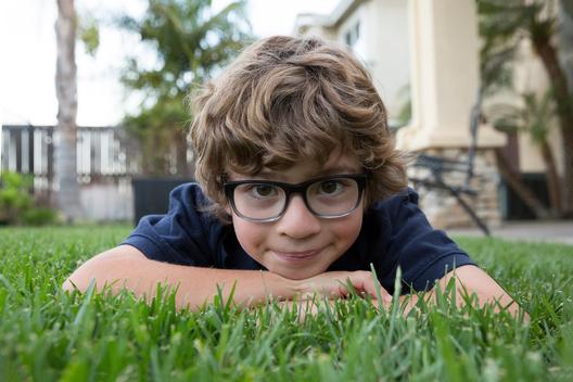 Portrait of young boy lying on front on grass, close-up