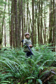 a young boy holding a rifle in the woods at Clayoquot Wilderness Resort