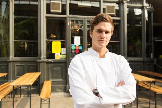 Young chef standing outside of work, arms folded