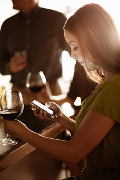 Businesswoman looking at cellphone in a wine bar