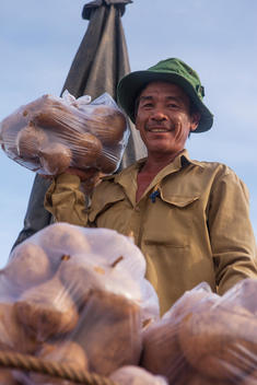 A man lifts bagged potatoes for sale from his boat in Can Tho\'s open market.