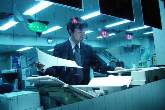 Young Man Working Inside Copy Bureau In Tokyo, Japan.
