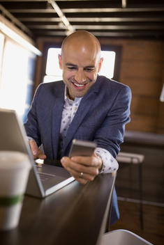 Businessman using laptop and cell phone in cafe