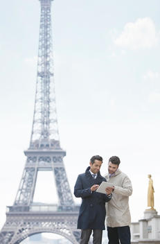 Businessmen using digital tablet by Eiffel Tower, Paris, France