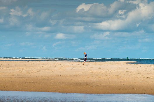 A small boy with ginger hair jumps vertically in the air on Holkham Beach in Norfolk