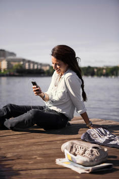 Happy businesswoman listening music while sitting on boardwalk at seaside